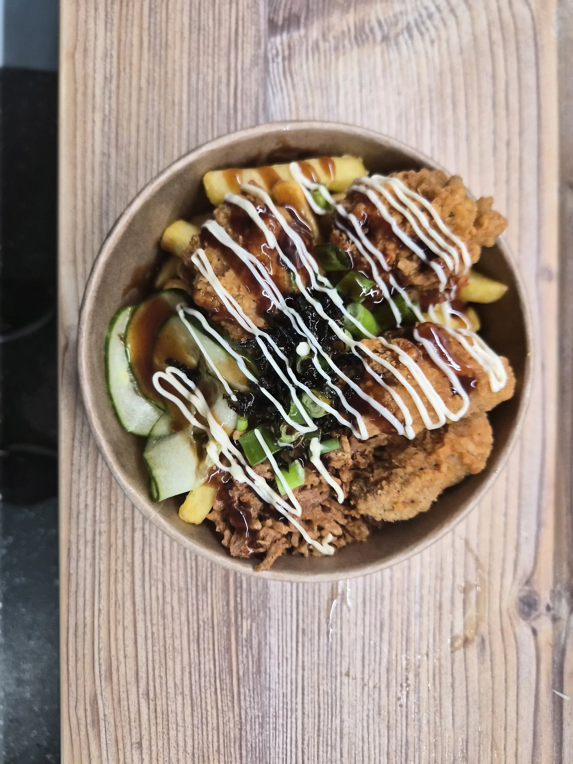 Loaded Fries mit Chicken Katsu in einer Schale auf einem Holztisch